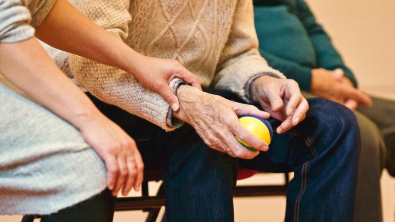 people sitting as older person holds ball