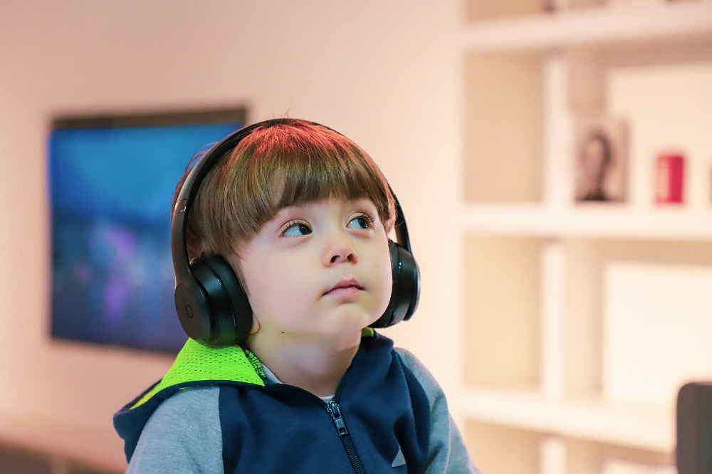 A young child in a hoodie, wearing headphones