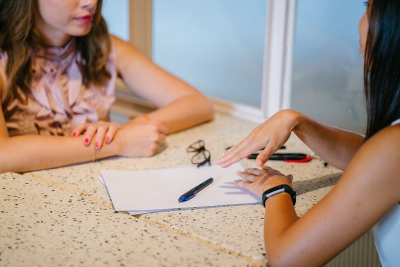 Two people sitting at a table with a piece of paper between them